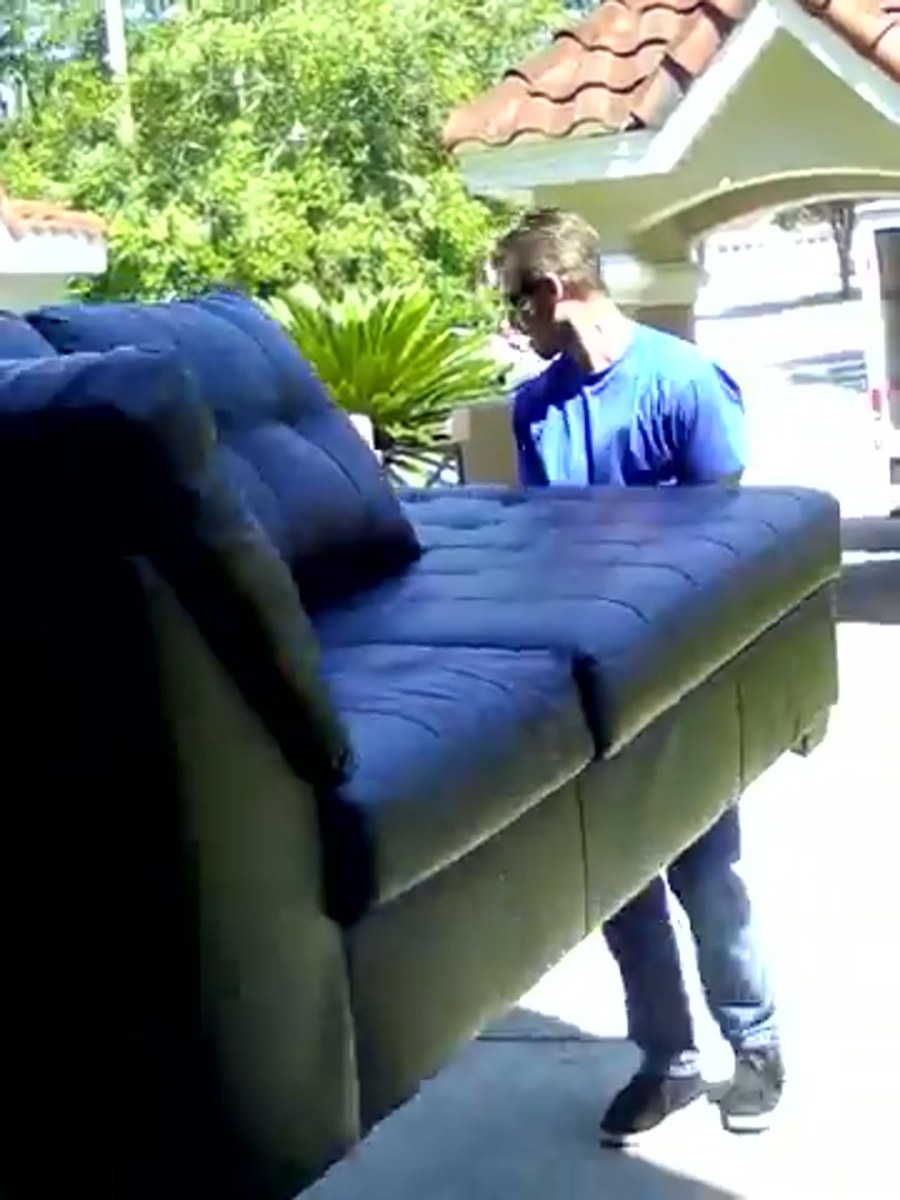 A Conan Moving crew carrying a wrapped piece into a Haltom City home